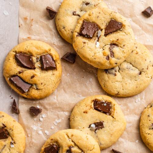 Overhead view of air fryer chocolate chip cookies scattered on a tabletop covered in parchment paper.