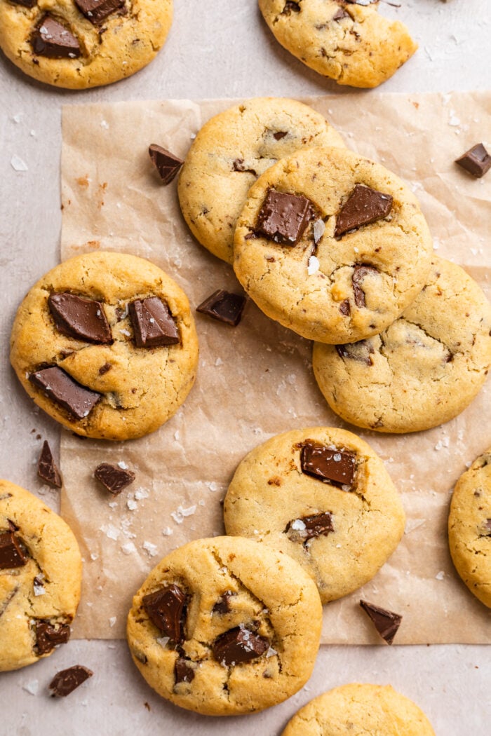 Overhead view of air fryer chocolate chip cookies scattered on a tabletop covered in parchment paper.