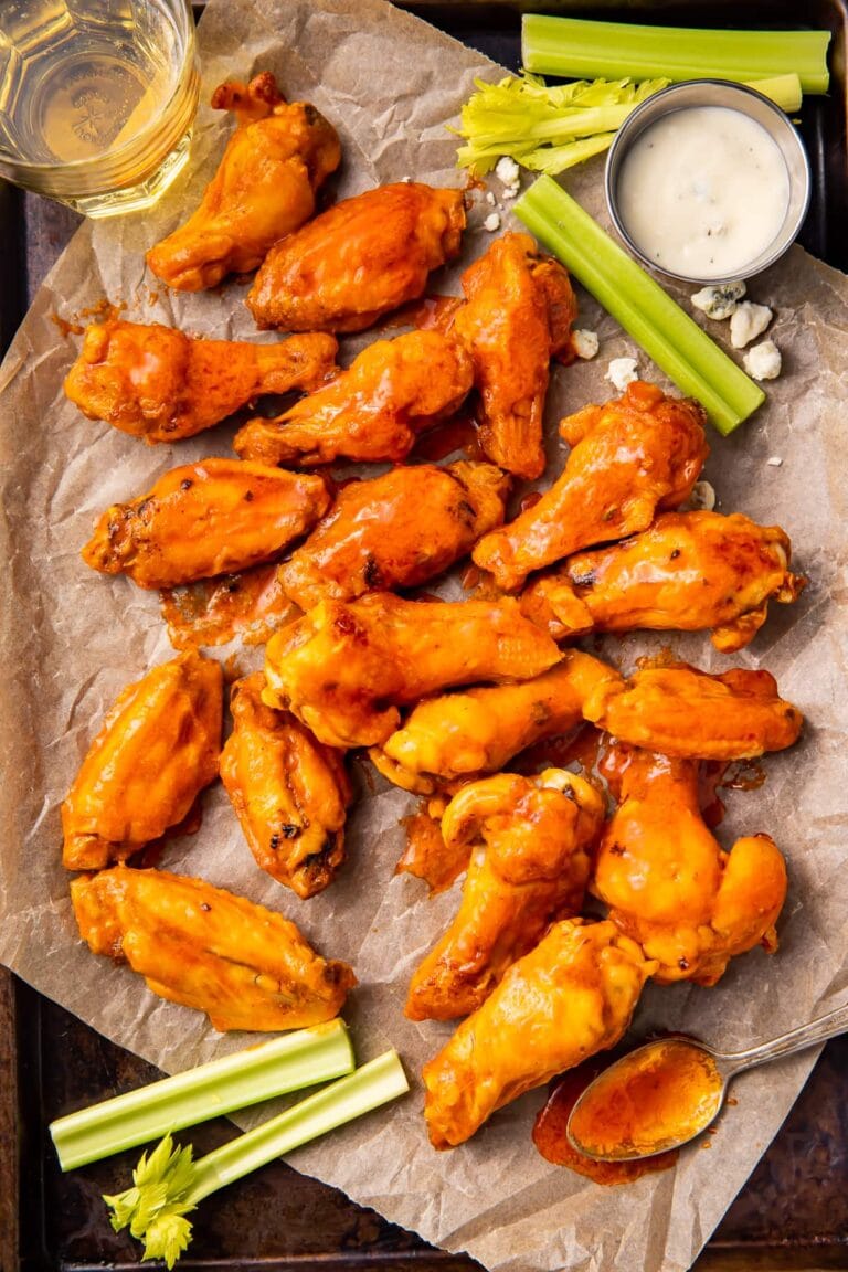 Air fryer frozen chicken wings on a baking sheet with parchment paper and celery sticks