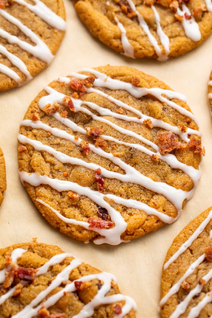 Bacon cookie butter cookies with a cinnamon glaze drizzle arranged on parchment paper.