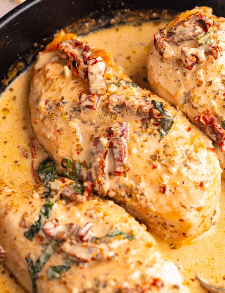Marry Me Chicken breasts in a cast-iron skillet with basil and sun-dried tomatoes.