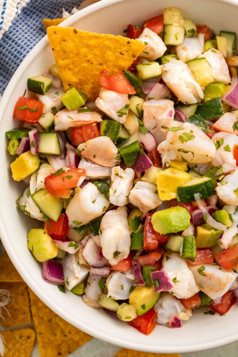 Overhead view of a bowl of easy shrimp ceviche with chunks of shrimp, red onion, cucumber, avocado, and tomatoes.