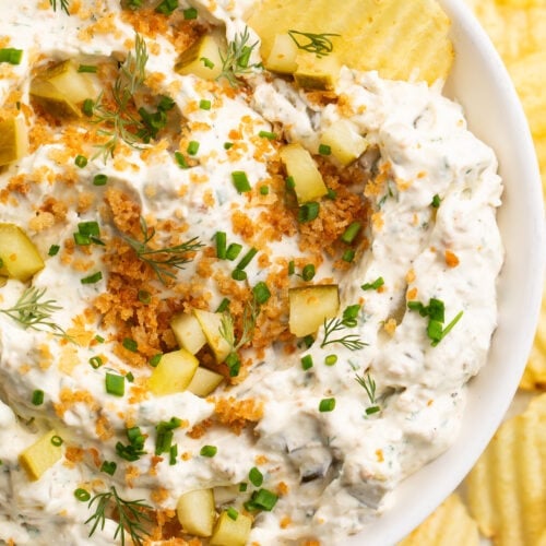 Close-up look at a large white bowl holding a fried pickle dip made with cream cheese, sour cream, dill pickles, and breadcrumbs.