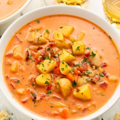 Overhead view of Manhattan clam chowder in a large white soup bowl with chunks of diced potatoes and chopped clams.