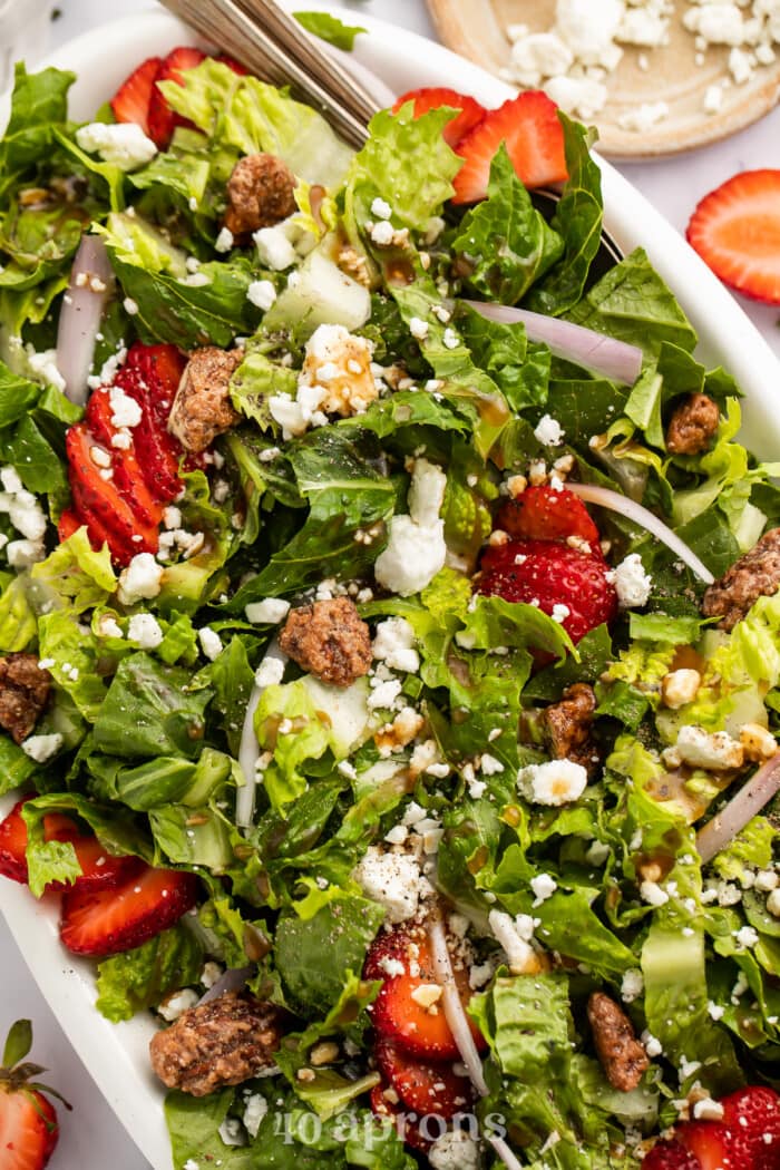 Close-up, overhead view of strawberry goat cheese salad with goat cheese crumbles and praline pecans.