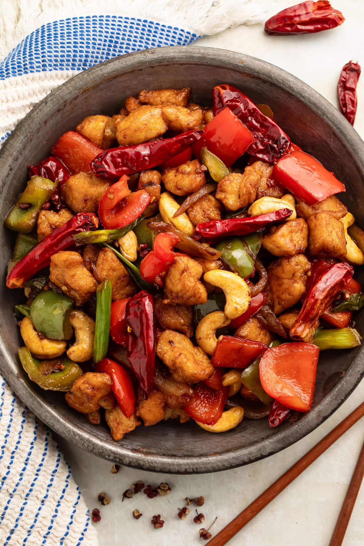 A bowl of Szechuan chicken on a table with chopsticks.